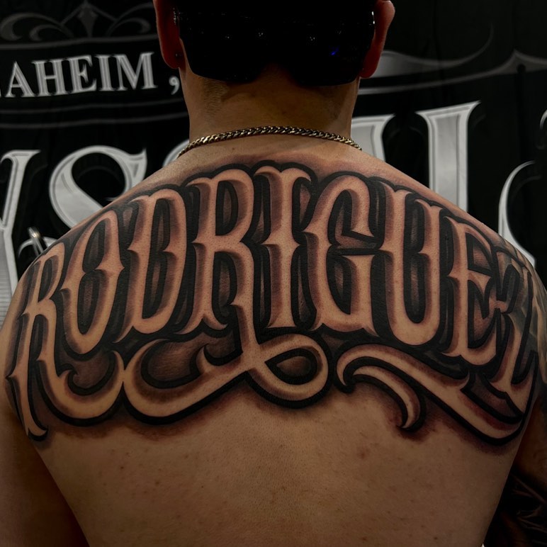 bold last name back tattoos for men